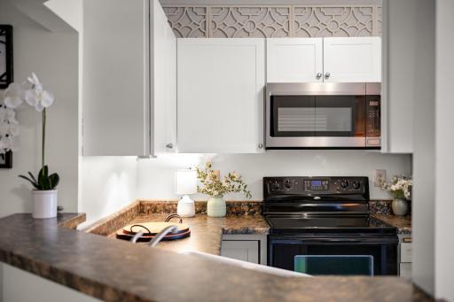 Bright kitchen features white cabinetry, generous counter space, and a convenient peninsula overlooking the main living area.