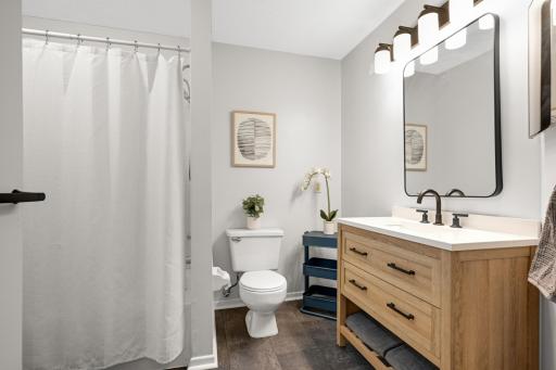 Fresh, inviting bathroom featuring an updated vanity, modern black fixtures, large mirror, and practical storage.