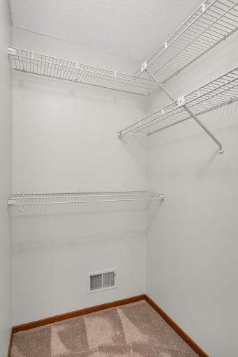 Spacious walk-in closet with wraparound shelving provides excellent clothing and storage space.