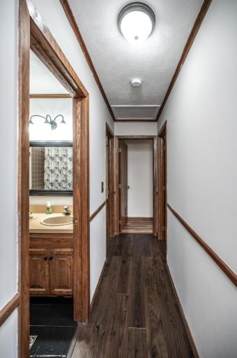 The main level hallway leading to a full bathroom and 3 bedrooms