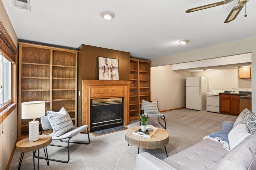 The Lower level family room features a gas burning fireplace, beautiful built-in shelves, and a kitchenette nearby.