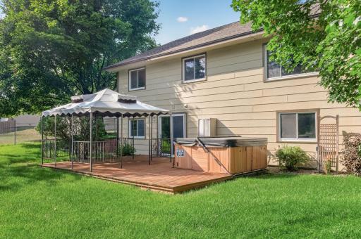 View of the covered deck patio and hot tub from the backyard. The sellers would like to include the hot tub in the sale.
