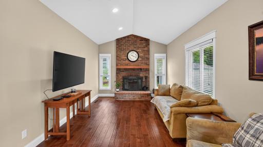 Vaulted ceiling, hardwood flooring and a wood burning fireplace make up the main level family room.