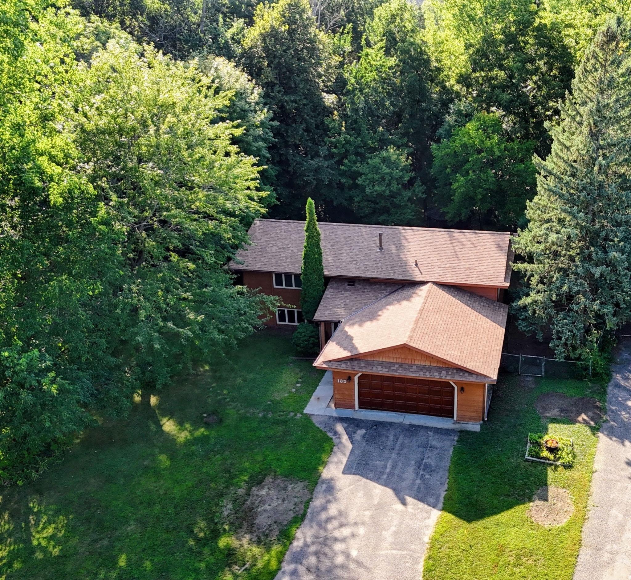 A beautiful aerial shot showcasing the front of the home with mature trees lining both sides and the backyard, plus a new roof installed in 2026.