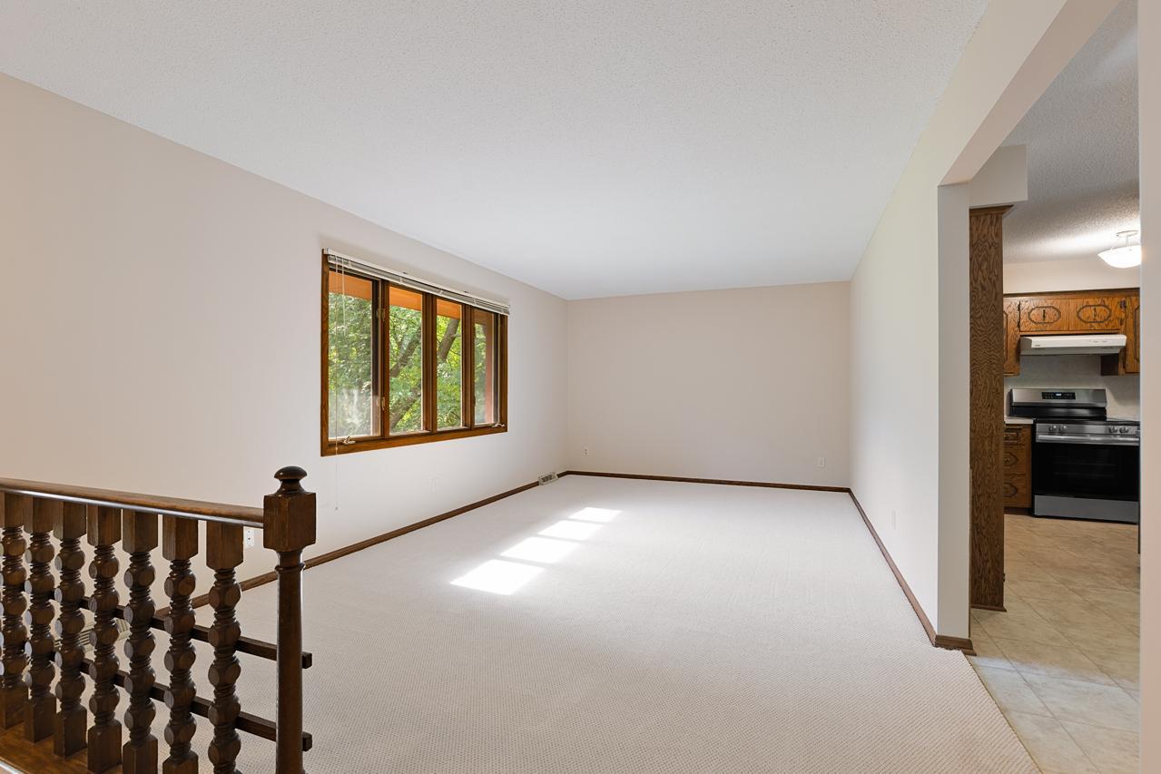 A view of the large living room, highlighting its large layout, new carpet, fresh paint, and natural light.