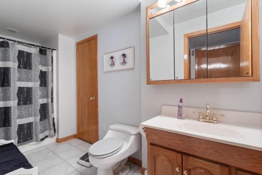 Convenient lower-level ¾ bath featuring heated tiled floors and a spacious linen closet. Perfectly located near the NASCAR-themed entertainment area and custom bar, making it easy and convenient for guests while entertaining.