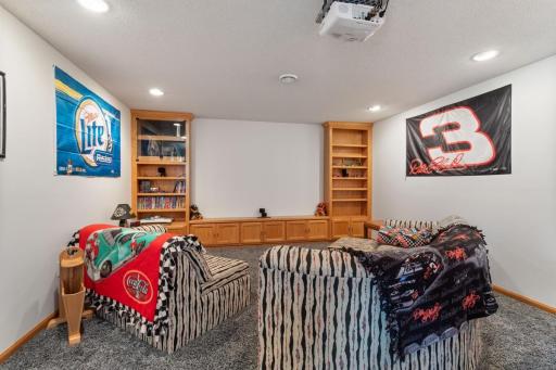 The ultimate entertainment space features a built-in movie projector that stays with the home, recessed lighting, built-in bookshelves and cabinetry. A fantastic setup for movie nights, race days and gatherings with family and friends.