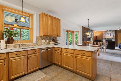 Kitchen with convenient snack bar seating and a window offering beautiful views of the screened porch, deck and mature backyard trees—bringing the beauty of the outdoors into the heart of the home.