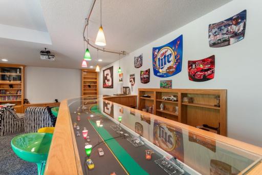 A one-of-a-kind conversation piece! This custom glass-topped bar features a miniature racetrack built right into the bar top, adding an unforgettable NASCAR-inspired touch to this incredible entertaining space.