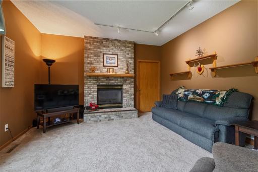 A unique double-sided gas fireplace with floor-to-ceiling brick surround connects the spacious living room and main-floor office, with a convenient door providing easy access between these inviting spaces.