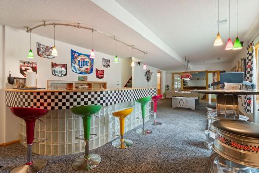 A 43’ x 13’ entertainer’s dream! Custom bar features racing-inspired black-and-white tile, glass block accents and colorful pendant lights. A cozy window-side seating area completes this wide-open NASCAR-themed space.