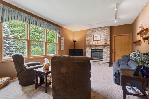 Spacious and cozy living room featuring beautiful backyard views and a warm gas fireplace with a striking floor-to-ceiling brick surround, creating an inviting gathering space for relaxing and entertaining.