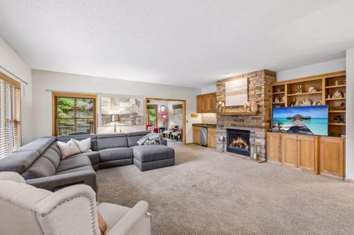 Living room with built-in maple cabinetry and a dramatic floor-to-ceiling stone gas fireplace.