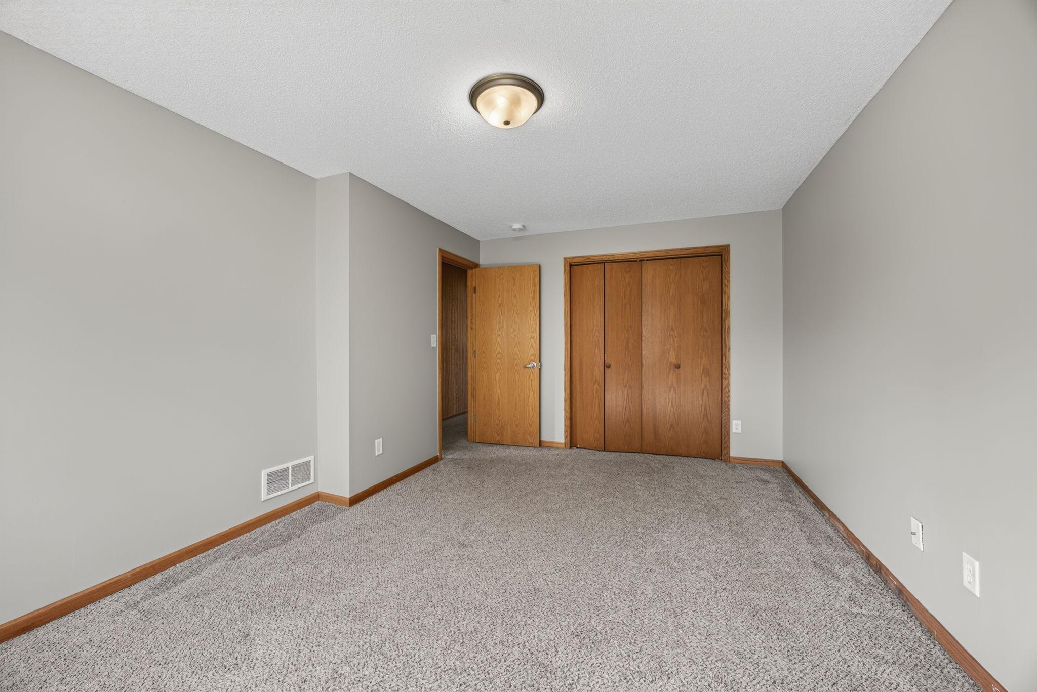 Bright and clean lower-level bedroom featuring spacious closets with plenty of room for storage.