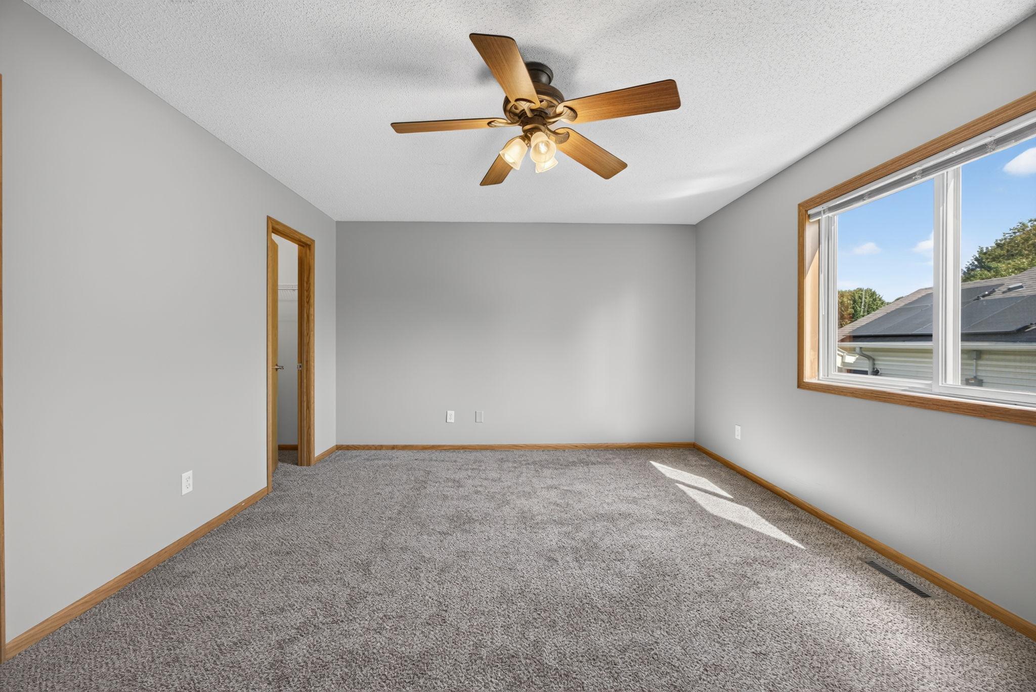 Sun-filled and spacious primary bedroom featuring two walk-in closets and convenient access to the main-floor bathroom, offering plenty of storage and everyday functionality.