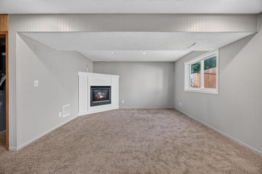 The lower-level living room offers a versatile second living space, perfect for movie nights, a teen hangout, or relaxing with family and friends. The cozy fireplace adds warmth and ambiance, making it an inviting retreat on cold Minnesota.