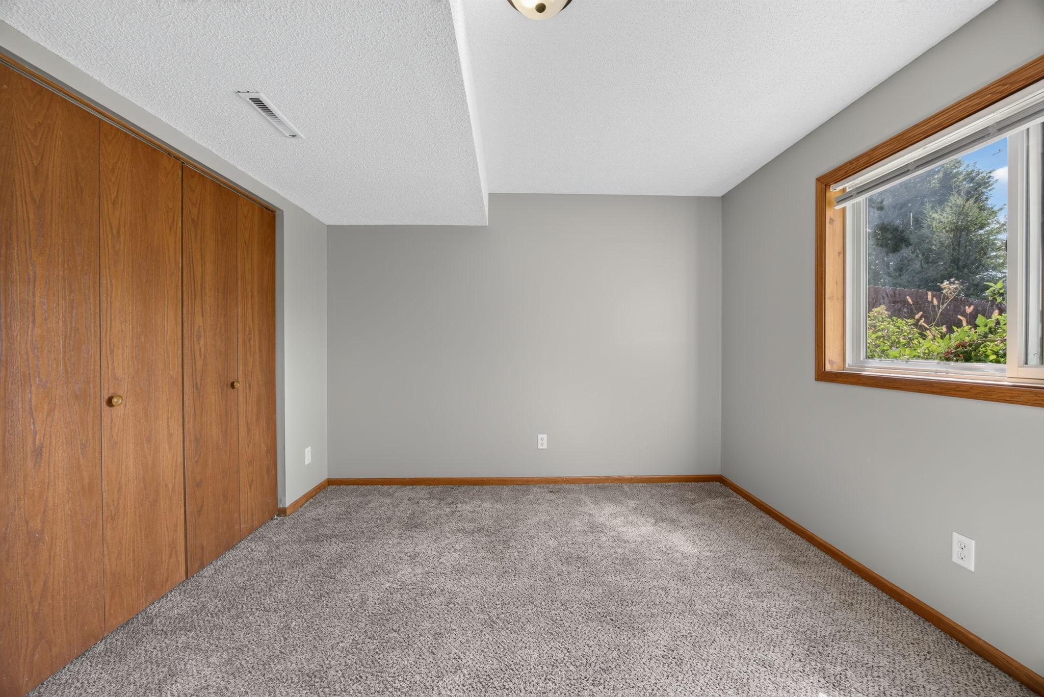 Bright and clean lower-level bedroom featuring spacious closets with plenty of room for storage.