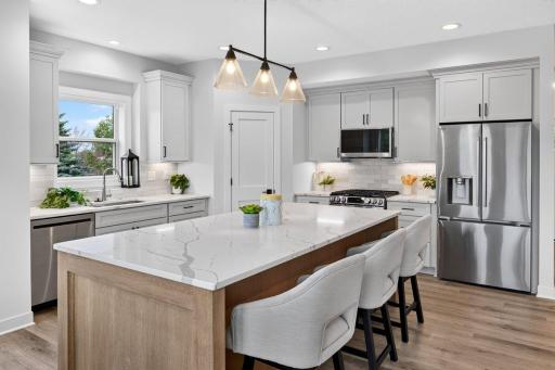 Stunning kitchen includes a massive center island, quartz countertops, tiled backsplash, stainless steel appliances and walk-in pantry.