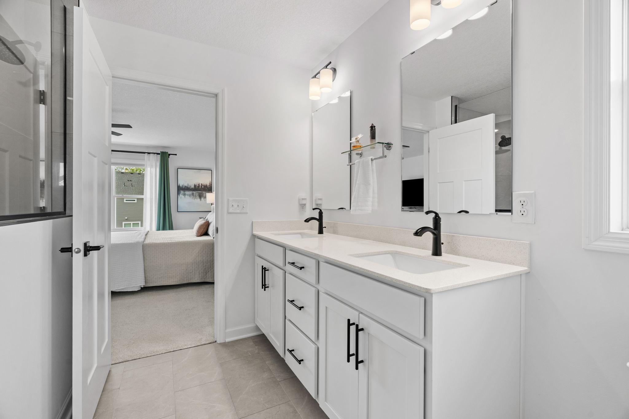 Primary Ensuite featuring dual sinks, quartz counters, upgraded Serenity Shower w/ floor-to-ceiling tile + dual shower heads & walk-in closet.