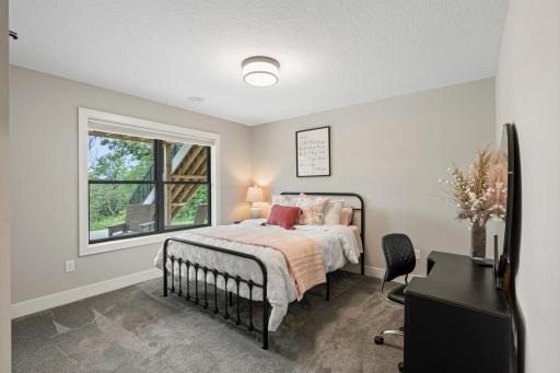 Comfortable lower level bedroom with a large window providing natural light and green views.