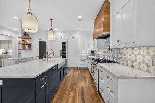 Custom enameled cabinetry features flat panel doors, glass accent doors, uppers are ceiling height, roll-out storage, under cabinet accent lighting, floating white oak shelves and an oversized âEat-Inâ center island