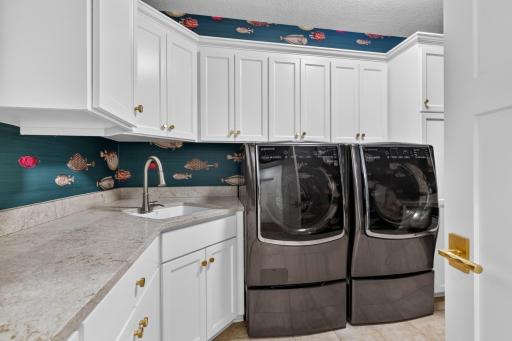 Laundry Room features enameled cabinetry w/ large quartz folding counter and under-mount sink.
