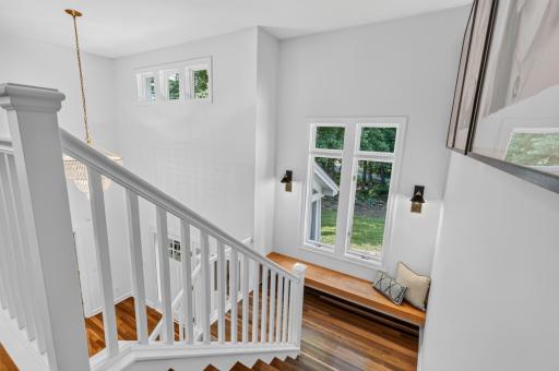 Onto the Upper Level ~ Large stair landing features a floating solid wood window bench and decorative sconces