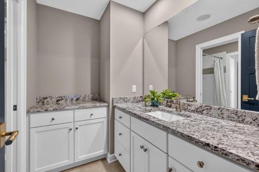 Private extension of the full bath includes an enameled vanity and an additional storage cabinet with granite countertops