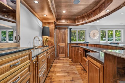 Roll-out storage, quartz countertops with stainless steel sink, glass door and curved raised bar. Walk-in storage closet in the bar w/ automatic light.
