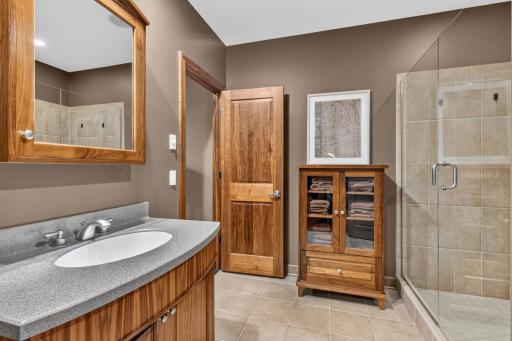 3/4 Walkthrough bathroom features custom black walnut vanity cabinet with bow front apron. "Furniture Like" black walnut linen cabinet with glass doors and decorative legs