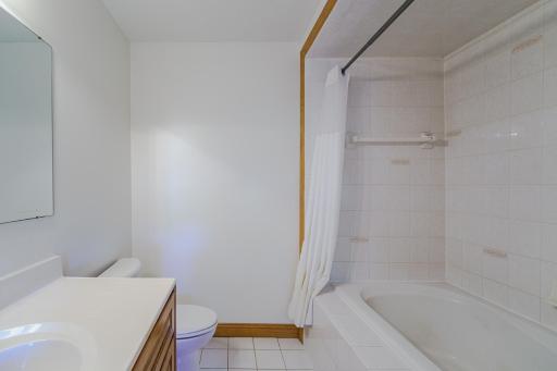 The main floor FULL bathroom has tile flooring and is located near the back hall.
