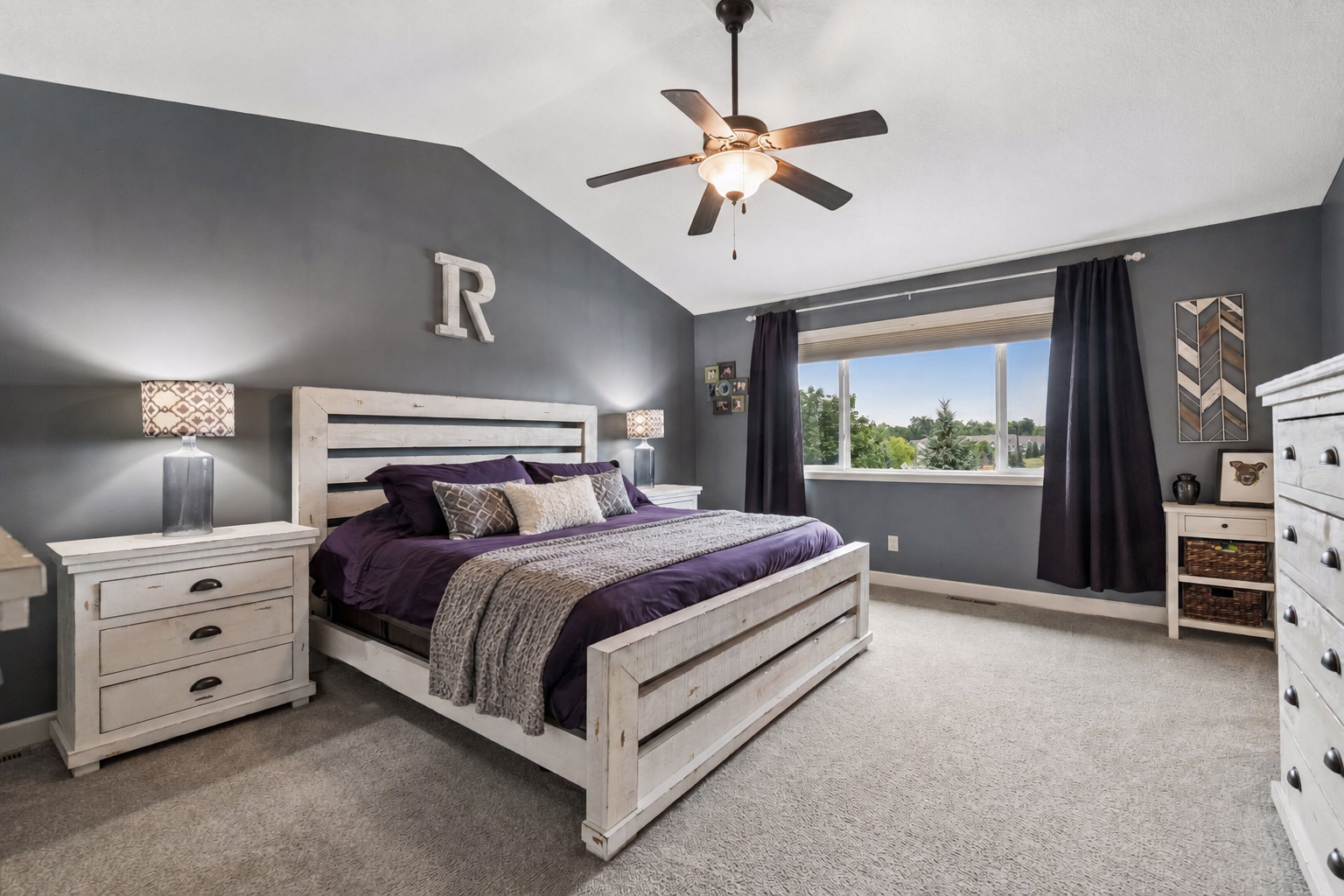 Primary suite with vaulted ceilings, fan and large picture window.