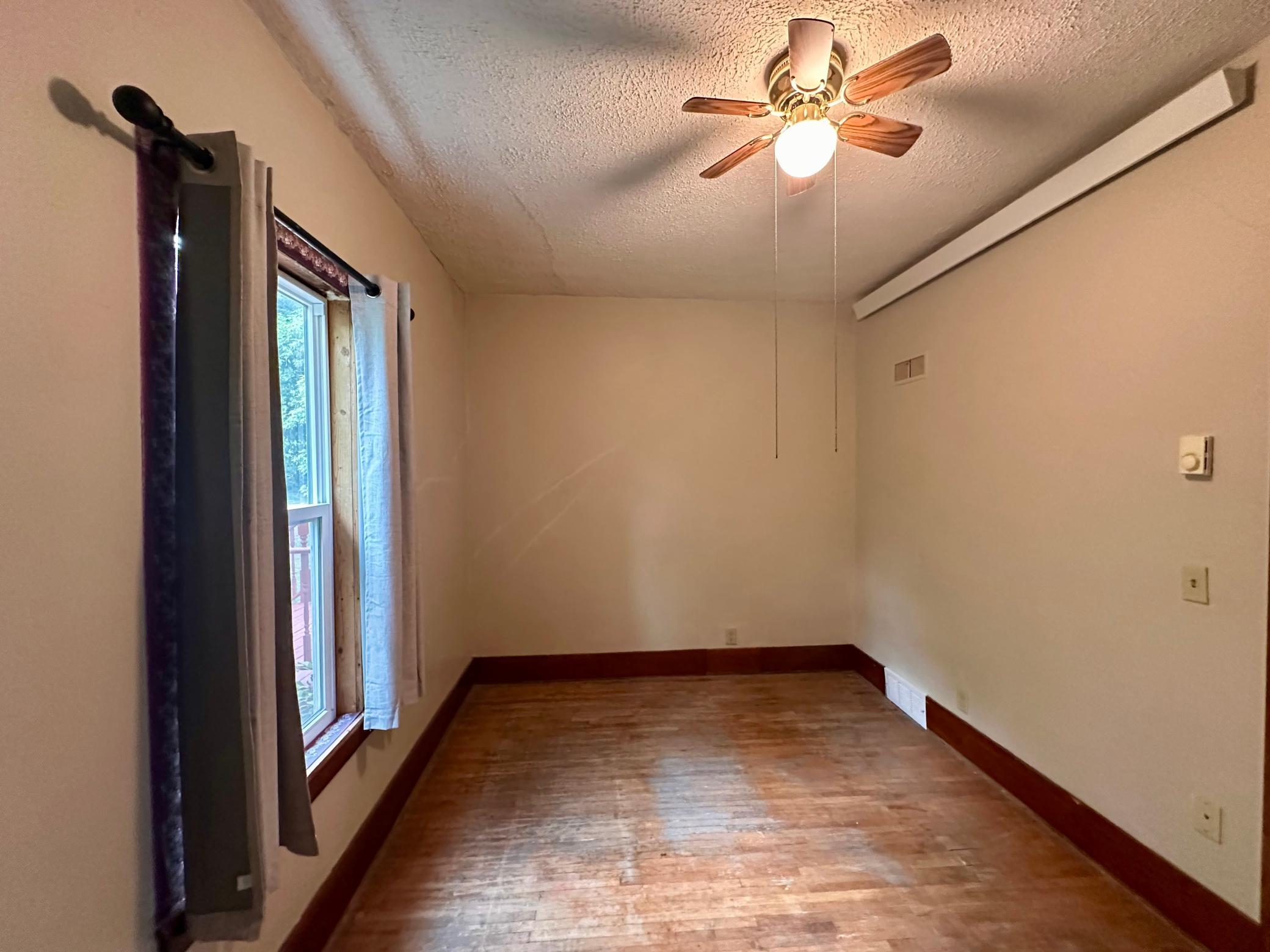 Bedroom 1 also features original hardwood flooring and newer window.