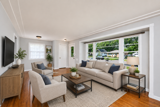 Virtually staged to showcase the possibilities — a bright, spacious living room highlighted by beautiful hardwood floors and an expansive picture window.