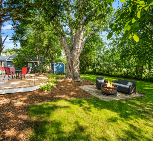 A backyard made for relaxing and entertaining — enjoy the spacious deck, cozy firepit area and beautiful mature trees that create a private, shaded retreat.