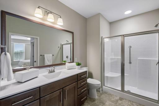 Private primary bath offering large walk-in shower with seat & grab bars, great lighting + a good sized vanity.