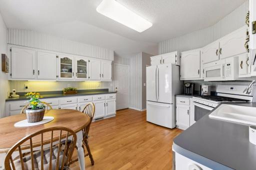 Bright eat-in kitchen with abundant cabinetry, generous workspace, and hardwood floors.