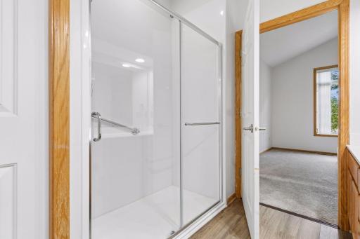 Accessible step-in shower stall in the primary ensuite, complete with sliding glass doors, built-in safety handrails, and low-maintenance surround.