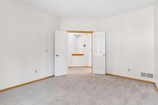 Double French door entry into the versatile main-floor bedroom, providing wide, seamless access from the central hallway.