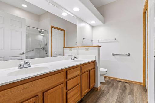 Spacious private primary bathroom (9'2" x 7'11") featuring an extended double-sink oak vanity, updated flooring, and accessible grab bars.