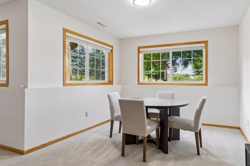Bright lower-level flex area with lookout windows framing tree views, ideal for board games, crafting, or a secondary workspace.