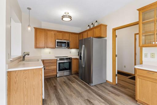 Functional kitchen equipped with updated appliances (2024), ample solid oak cabinetry, updated hard-surface flooring, and an open pass-through to the living room.