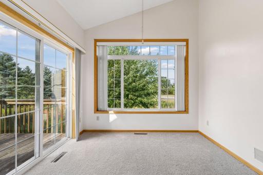 Vaulted four-season sunroom bathed in natural light, featuring panoramic windows and direct sliding glass door walkout access to the deck.