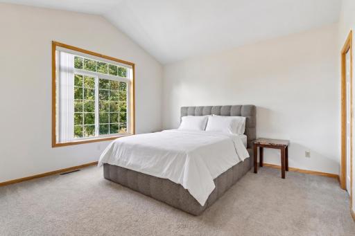 Spacious main-floor primary suite (13'6" x 13'8") featuring vaulted ceilings, a large picture window, and direct access to a private ensuite bath.