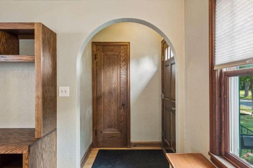 Charming arched entry with natural woodwork and hardwood flooring.