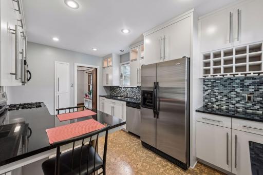 Another view of kitchen featuring breakfast bar and coffee/wine bar next to refrigerator.