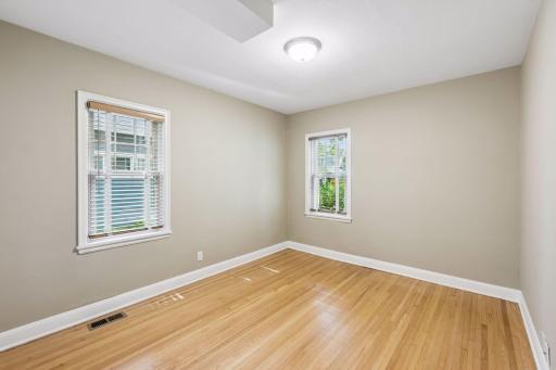 Main floor front bedroom with newer thermal pane windows and original hardwood flooring.