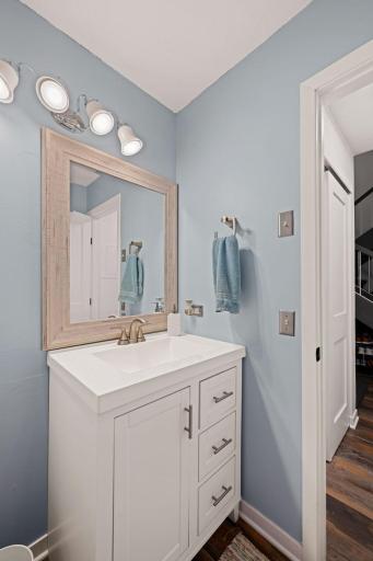 Convenient main-floor half bath featuring a white vanity, contemporary hardware, and framed mirror.