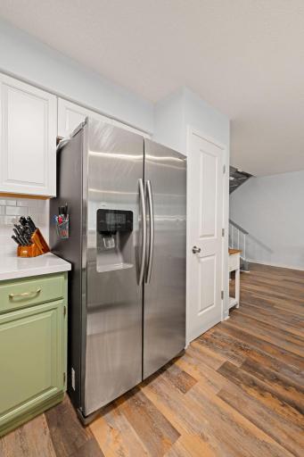 Additional view highlighting the full-size stainless-steel refrigerator, nearby pantry storage, and easy access to the main living area.