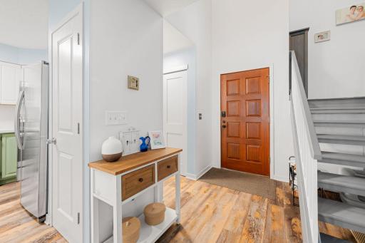 Welcoming entry featuring a wood front door, convenient access to the kitchen, and staircase leading to the private upper level.